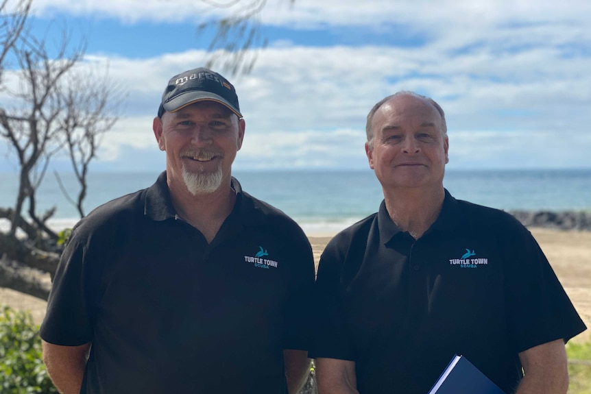 Two men stand at Bargara beach.