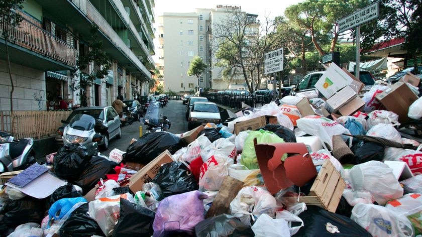 Naples residents park their cars next to piles of garbage