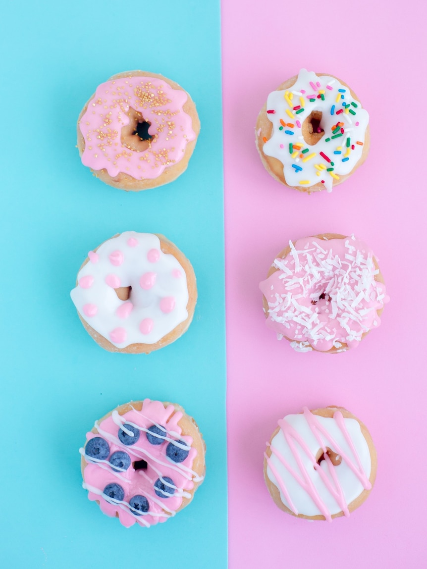 Six assorted donuts on a pink and blue background