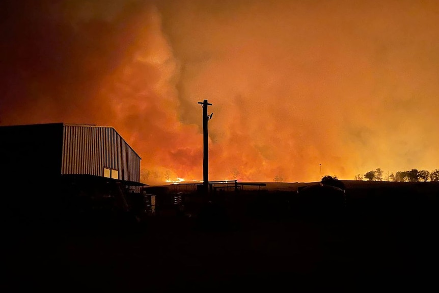 Glow from flames on horizon with shed in foreground