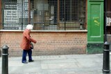 An elderly woman walks up a street