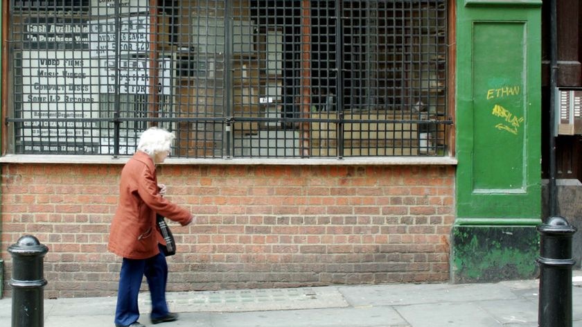 An elderly woman walks up a street