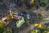 Rescuers operate at the site where a firefighting plane crashed after a water drop as a wildfires burn in Greece.