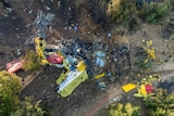 Rescuers operate at the site where a firefighting plane crashed after a water drop as a wildfires burn in Greece.
