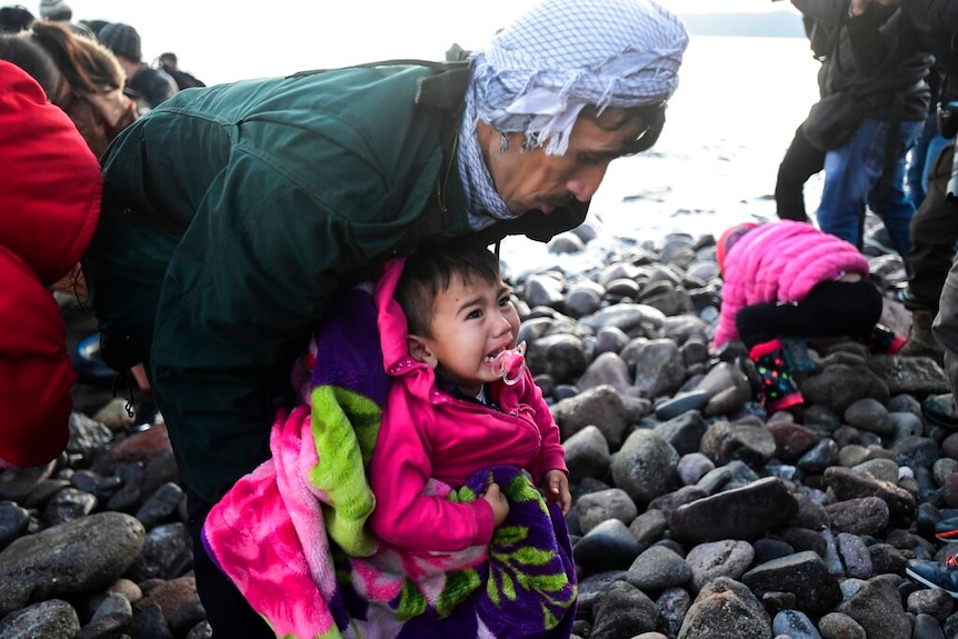 A child cries in the hands of a man as migrants arrive at the village on the Greek island of Lesbos.