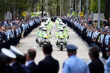 A police motorcade with thousands of officers forming a guard of honour.
