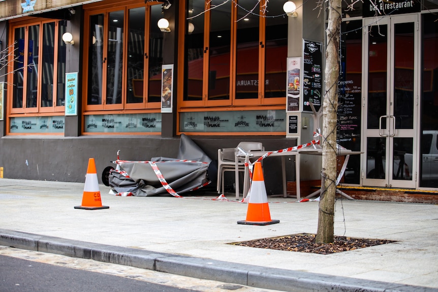 A footpath outside a restaurant in Perth's CBD with a section cordoned off by orange cones and tape.
