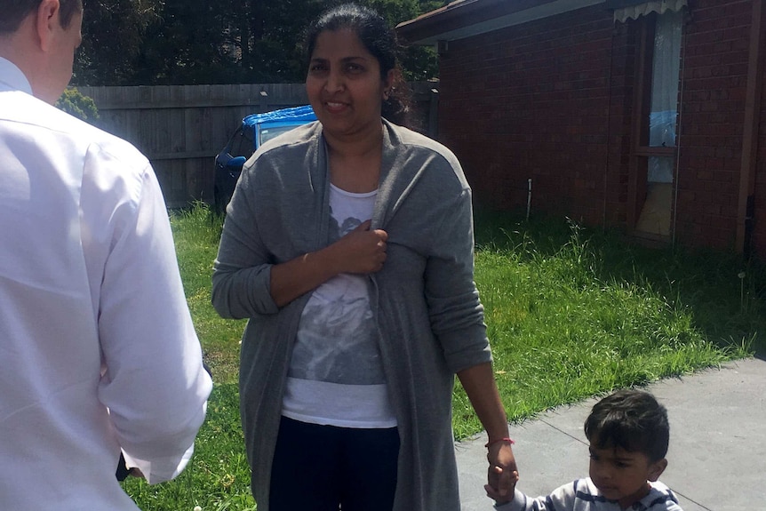 Vanda Kumar talking to a journalist while holding a child's hand.