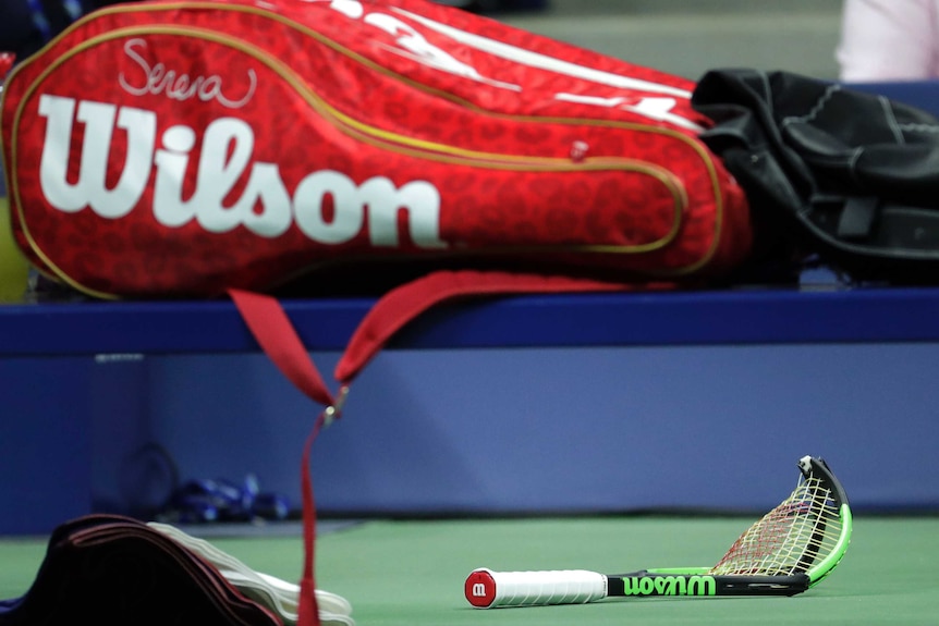 Serena Williams' broken racquet lies on the ground under her racquet bag on her on-court seat.