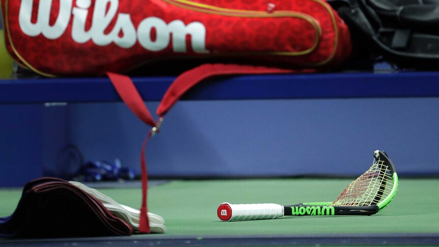 Serena Williams' broken racquet lies on the ground under her racquet bag on her on-court seat.
