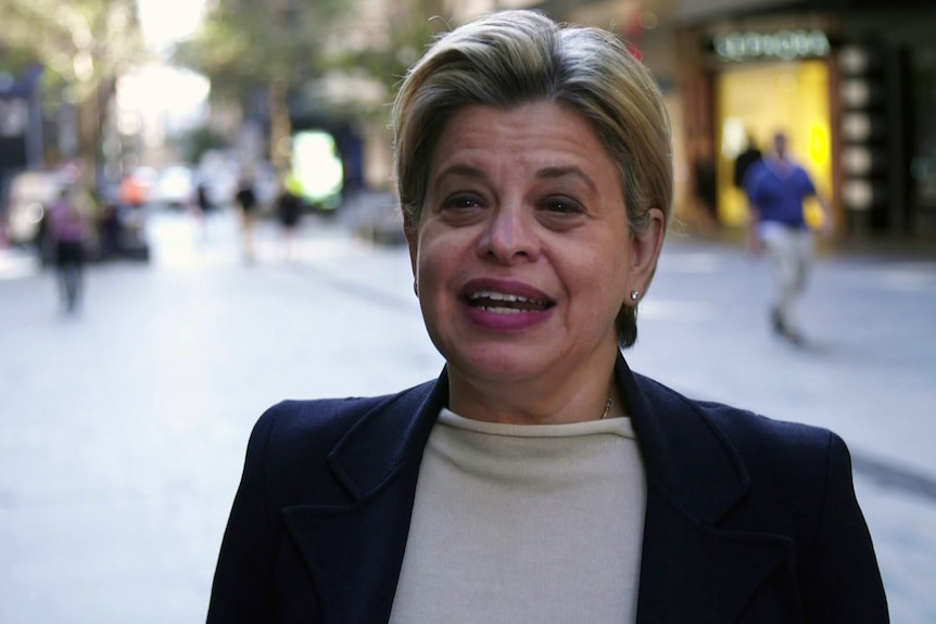 A woman wearing a dark jacket over a white top.