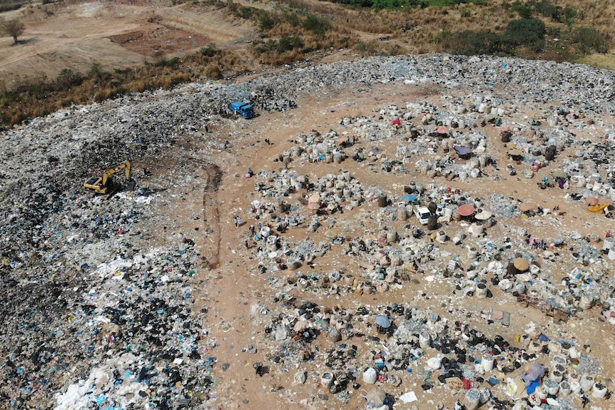 An aerial shot of a clearing with piles of rubbish bags and waste.