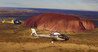 Two aircraft from the Professional Helicopter Services company flies past Uluru.