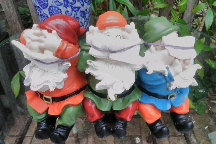 Three garden gnomes wearing face masks.