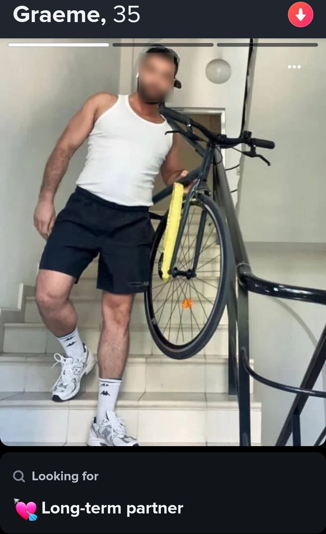A man standing on stairs with a white singlet holding a bike