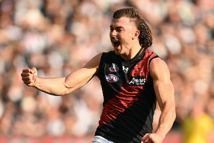 A man in red and black wearing a mullet celebrates.