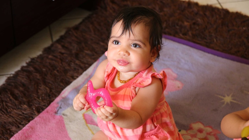 One of Megan Naden's twin girls holds a teething ring at the Gomeroi gaaynggal centre in Tamworth.