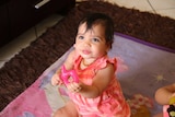 One of Megan Naden's twin girls holds a teething ring at the Gomeroi gaaynggal centre in Tamworth.