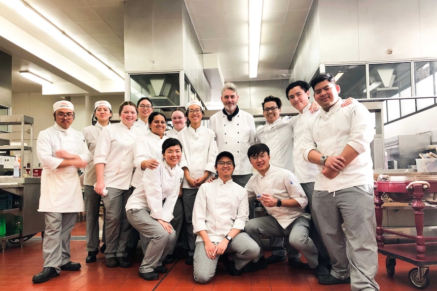 Rupal Bhatikar with classmates at William Angliss Institute in their black and white chefs' uniforms.