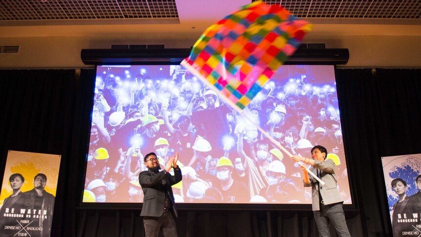 Badiucao and Denise Ho wave a flag.