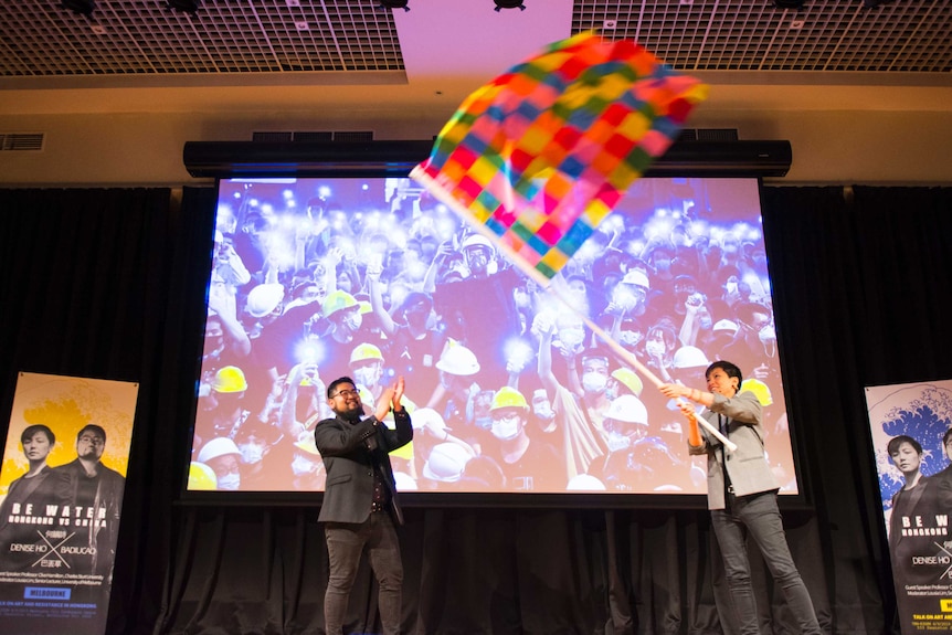 Badiucao and Denise Ho wave a flag.