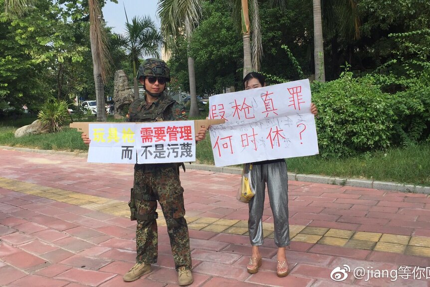 Two people stand holding placards to protest the arrest of Jiang Zhiping