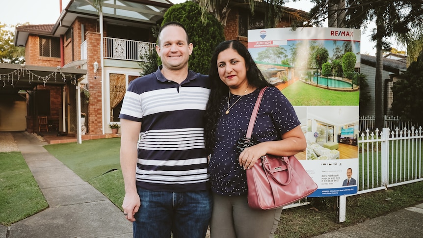 A man and a woman hugging in front of a house