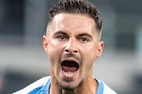 A Melbourne City A-League player yells out as he pumps his fists while celebrating a goal against Western United.