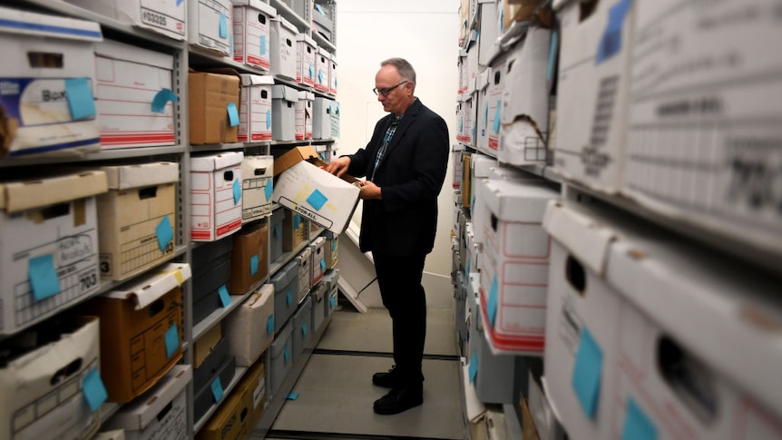 An archivists checks boxes in a large archive