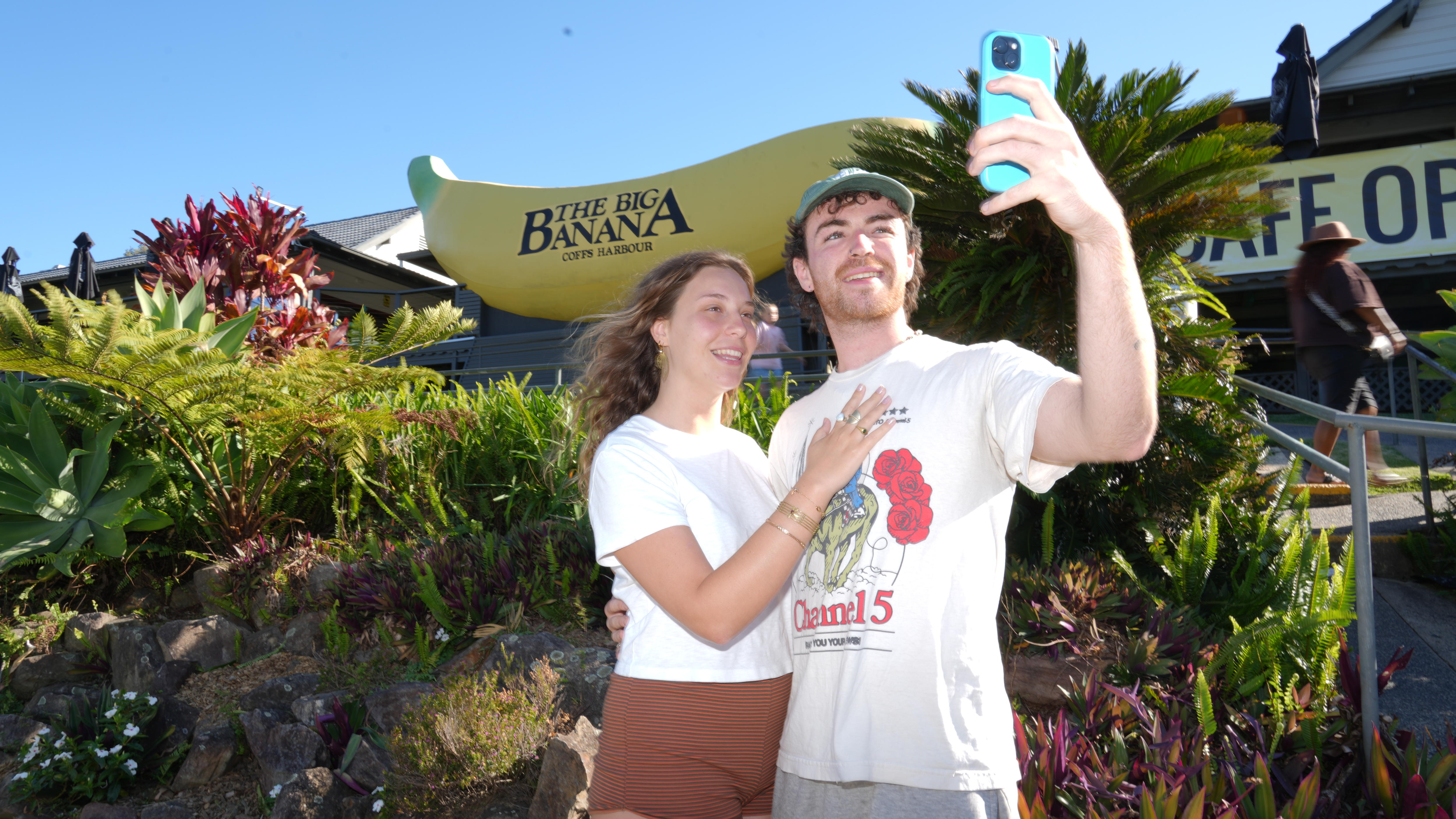 Young woman and man pose for phone selfie photo below Big Banana.