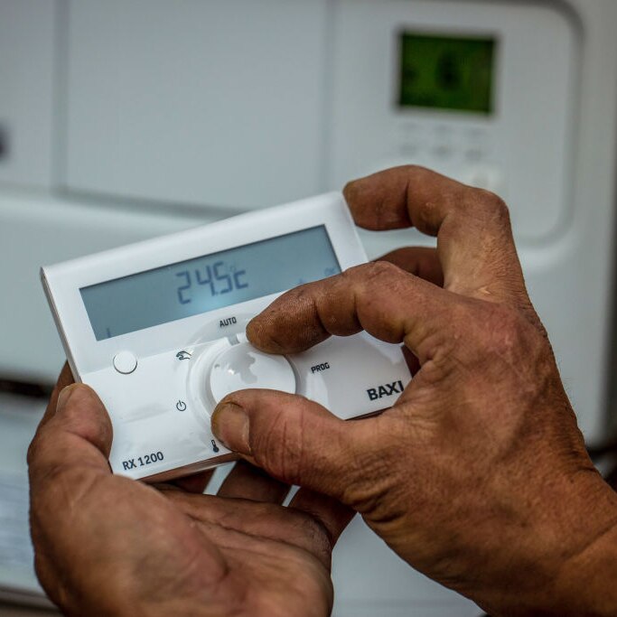 A technician adjust the temperature on a remote air conditioning thermostat