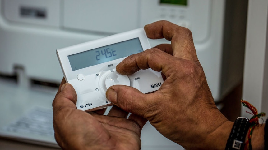 A technician adjust the temperature on a remote air conditioning thermostat