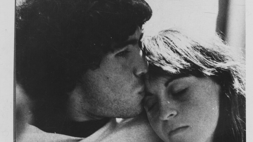 A black and white image of the couple embracing, Villafane laying her head on Maradona's chest.