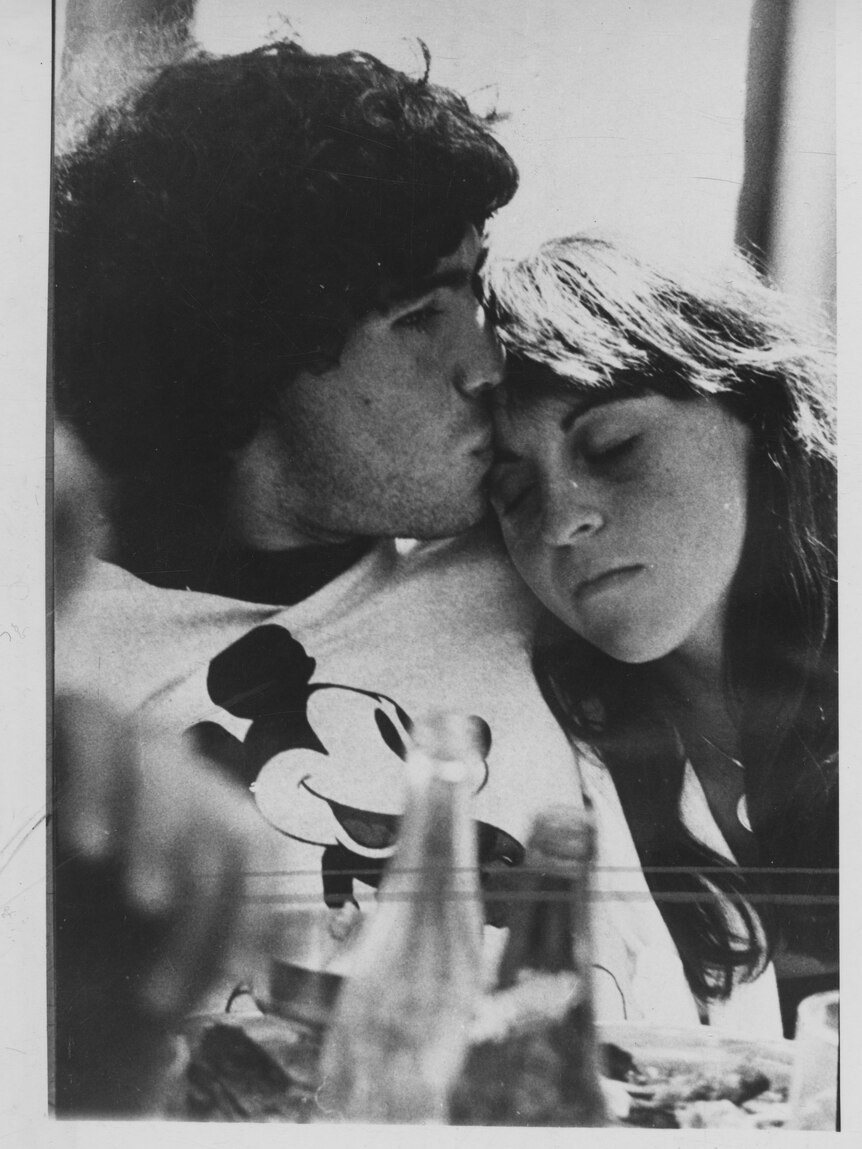 A black and white image of the couple embracing, Villafane laying her head on Maradona's chest.