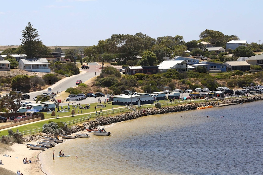 An aerial shot of a river with boats, a carpark and holiday houses.