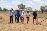 Premier Annastacia Palaszczuk with the Macmillan family and other politicians walking along a wild dog proof fence.