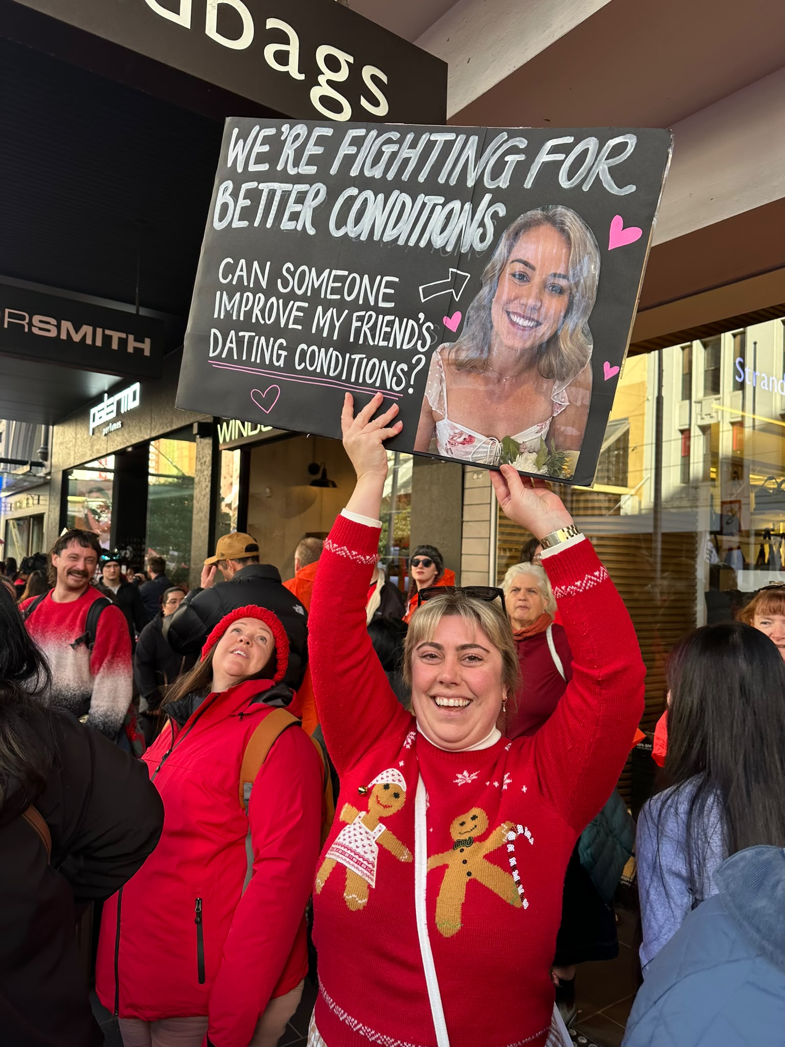 A woman at a protest holds a sign about educational conditions.