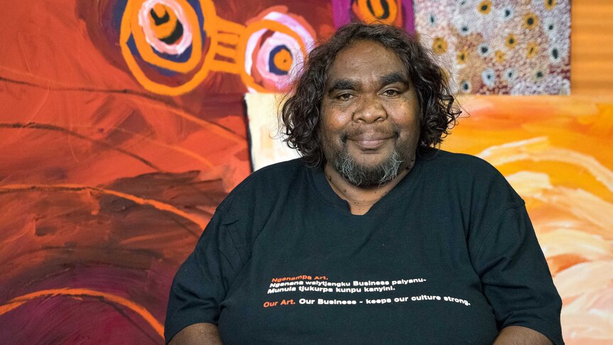 Indigenous woman Barbara Moore sits in a chair at an art gallery