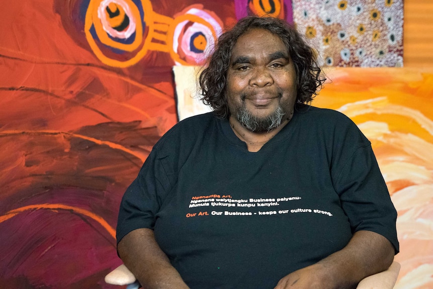 Indigenous woman Barbara Moore sits in a chair at an art gallery