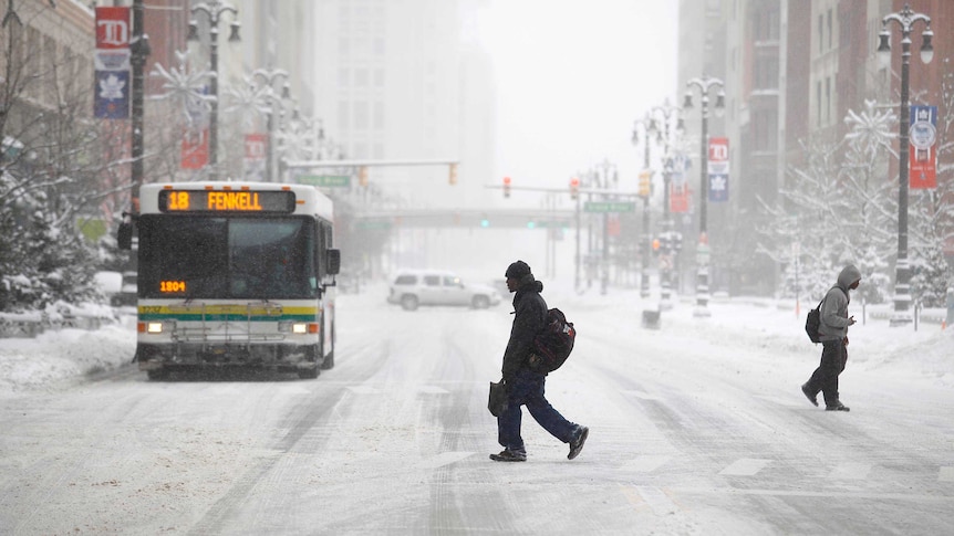 Pedestrians cross a snow-covered street in in Detroit during record breaking freezing weather.