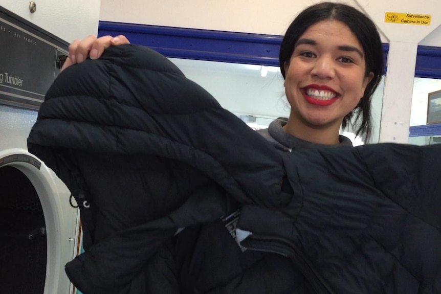 Smiling woman holding a cleaned puffer jacket