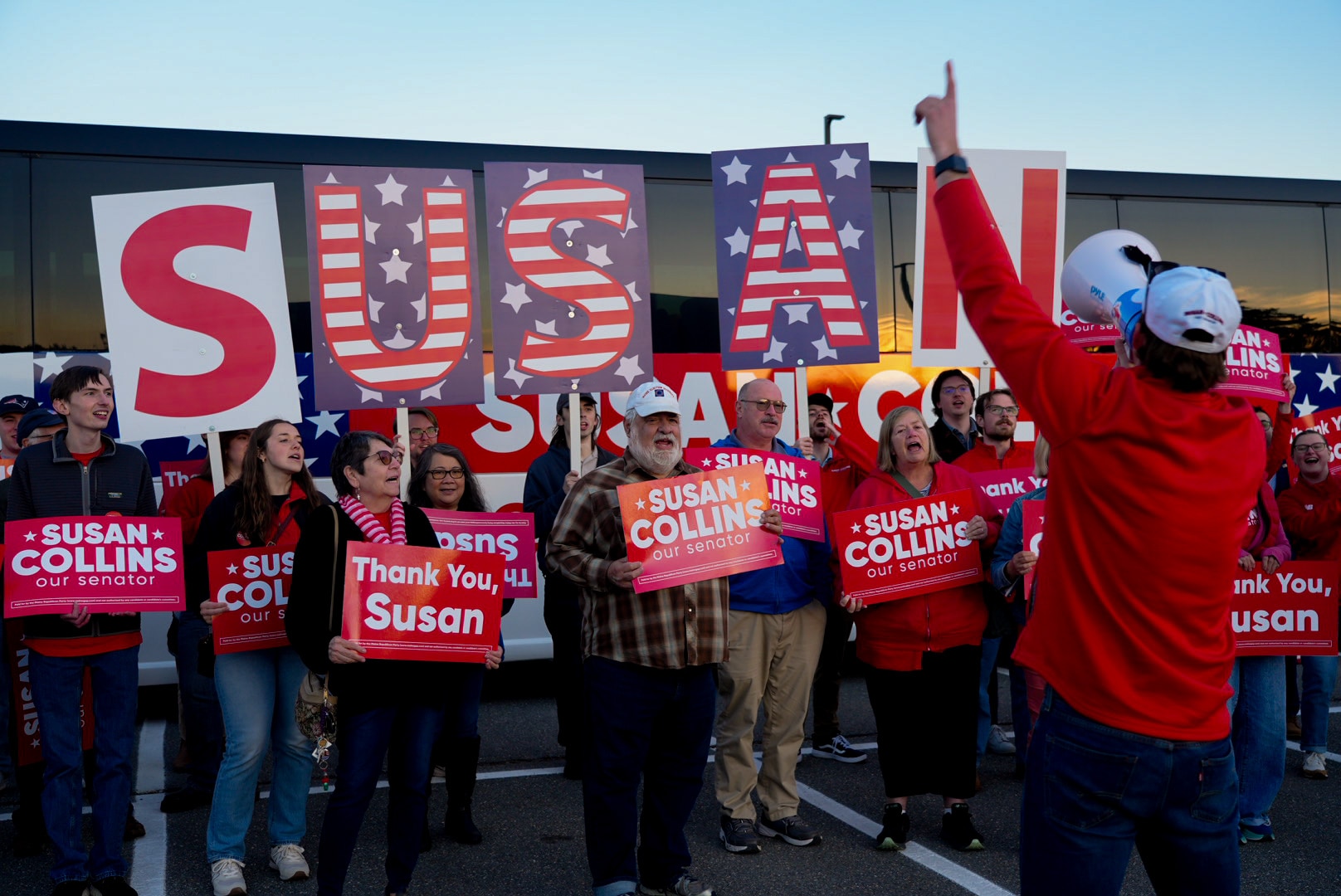 People hold signs and banners supporting Susan Collins.
