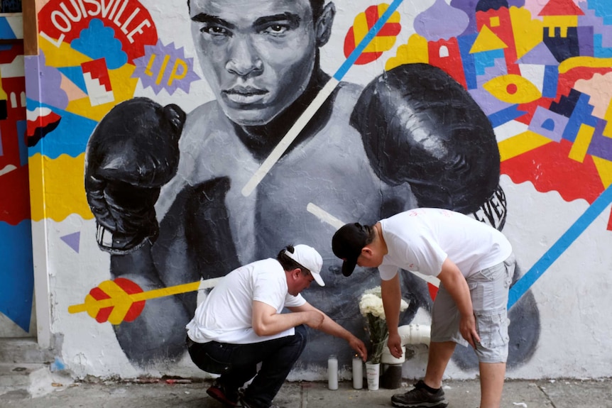 Employees of Joe's Pizza build a makeshift memorial to the late Muhammad Ali near a mural