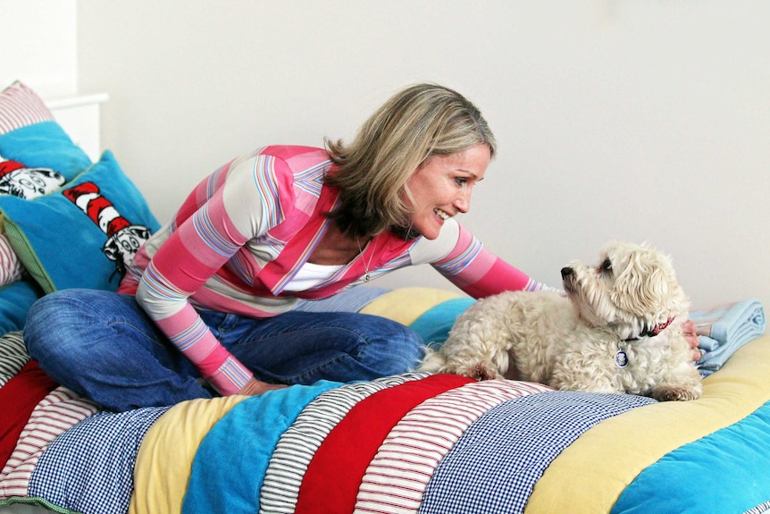 Kasey and Max look at one another on the bed representing the special bond between owner and pet dog.