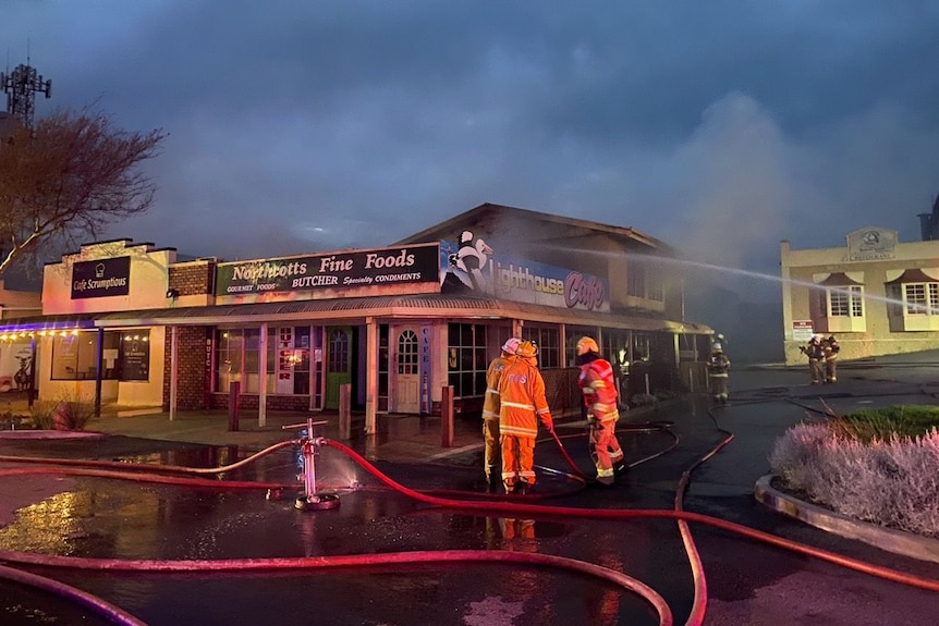 A building on fire with firefighters out the front.