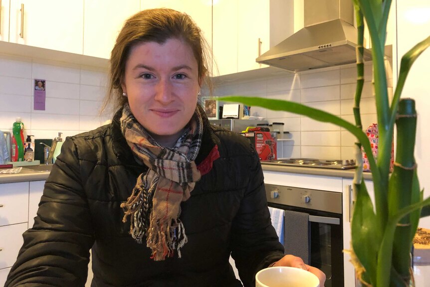A women holding a mug in a kitchen.