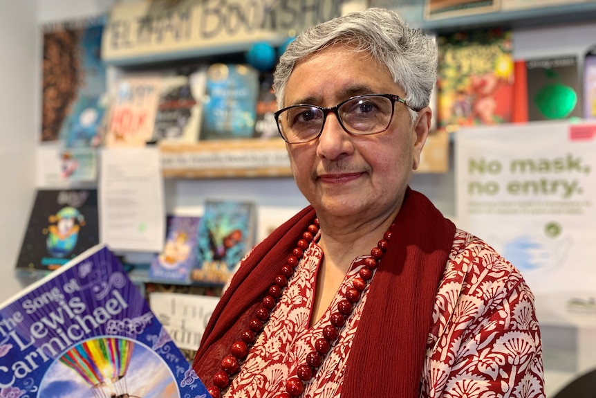 Meera Govil holds a book while standing behind the counter at her bookshop