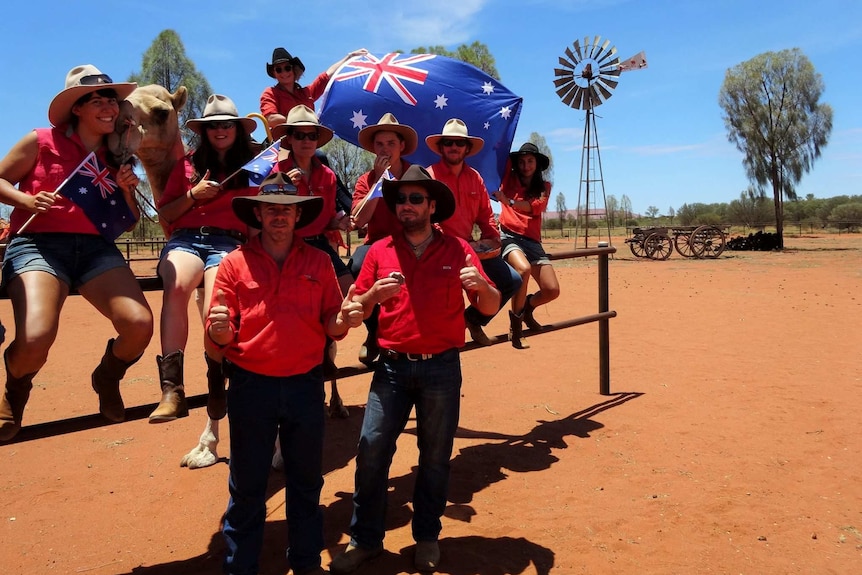 A group of people in the desert with a camel and an Australian flag