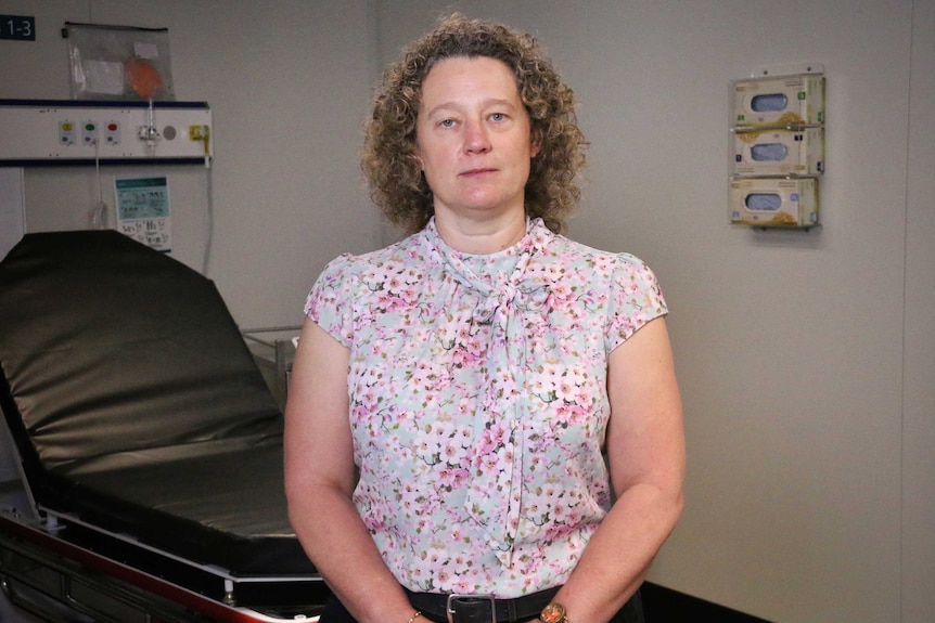 A woman stands in a patient room at a doctor's clinic