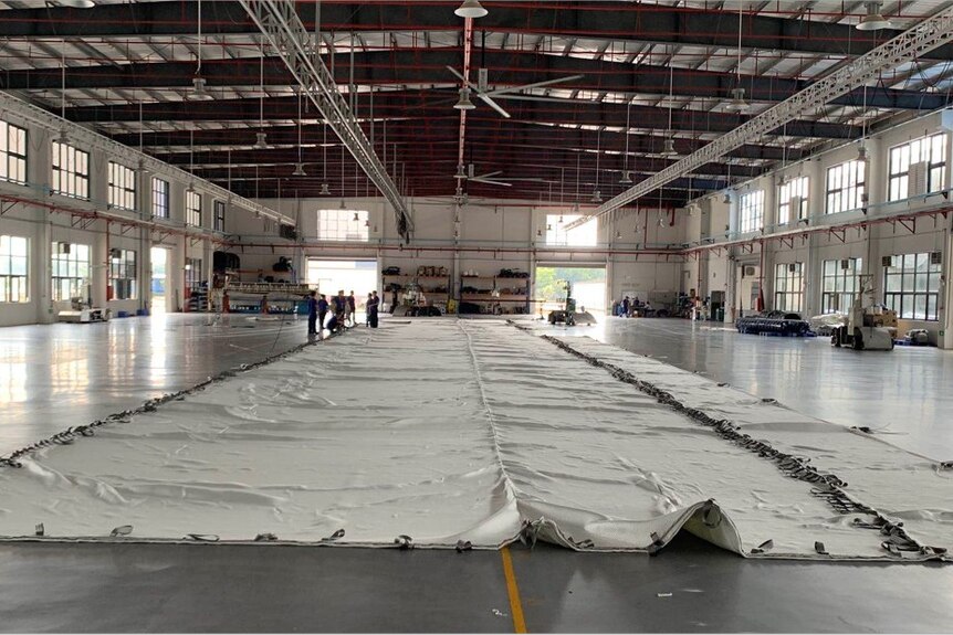 a large white sheet of material lays on the floor of a warehouse